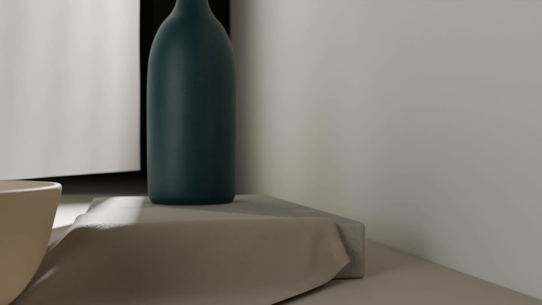 The petrol-colored vessel, cropped at the top, on a plinth covered with pale linen. On the left, the rim of a pale bowl.